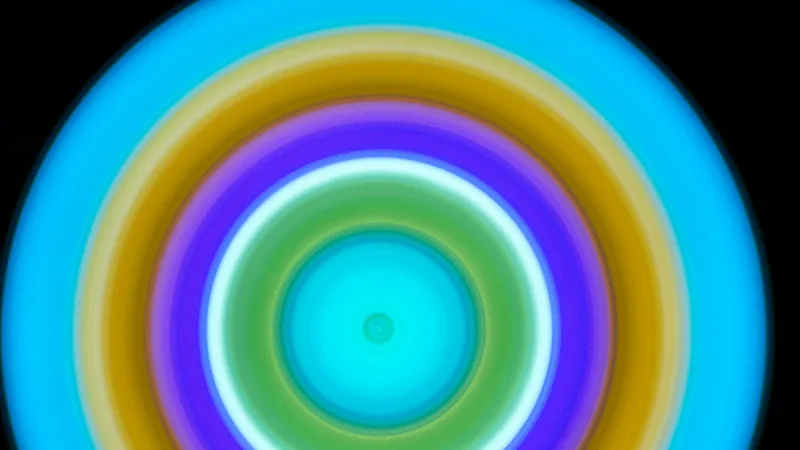 Wide abstract artwork with concentric cyan, gold, violet, white, and green light rings